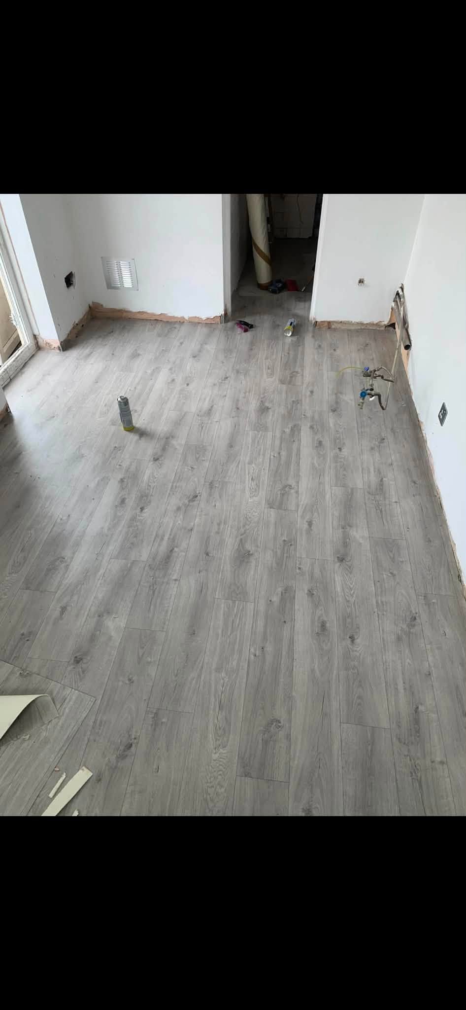 Grey oak laminate flooring being fitted in a living room