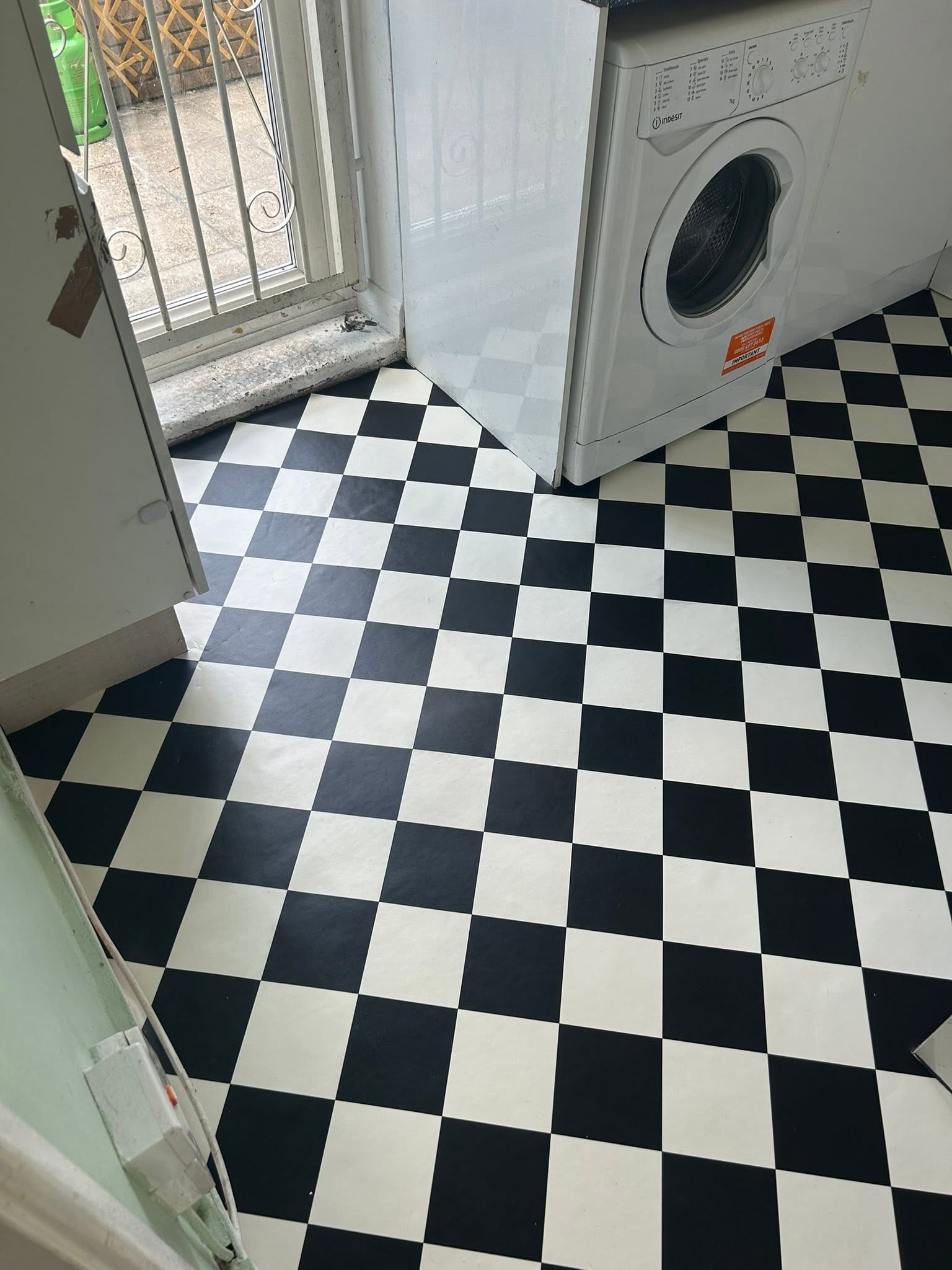 Black and white checkerboard vinyl flooring in a utility room